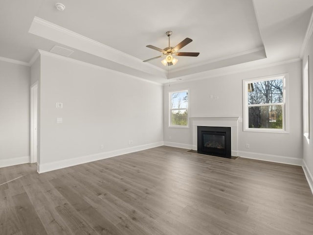 unfurnished living room with hardwood / wood-style flooring, ornamental molding, and a raised ceiling