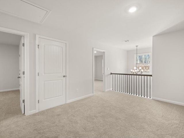 carpeted spare room featuring an inviting chandelier