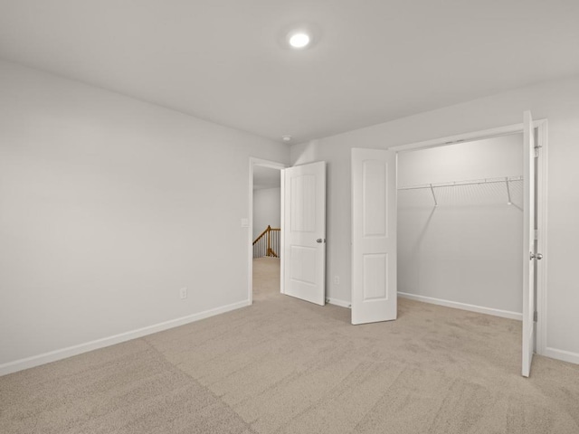 unfurnished bedroom featuring light colored carpet and a closet