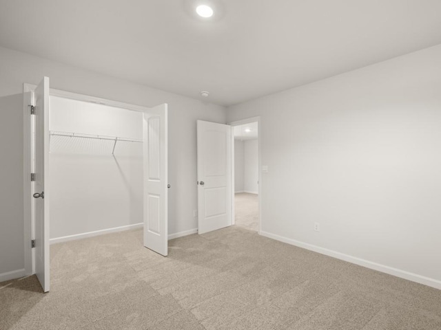 unfurnished bedroom with a closet and light carpet