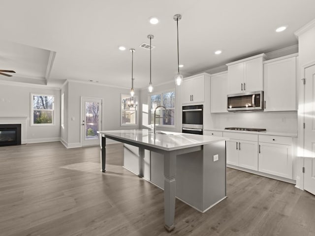 kitchen with hanging light fixtures, a breakfast bar area, white cabinets, and a center island with sink