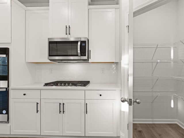 kitchen featuring backsplash, hardwood / wood-style flooring, white cabinets, and appliances with stainless steel finishes