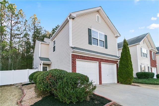 view of side of property with concrete driveway, brick siding, fence, and an attached garage