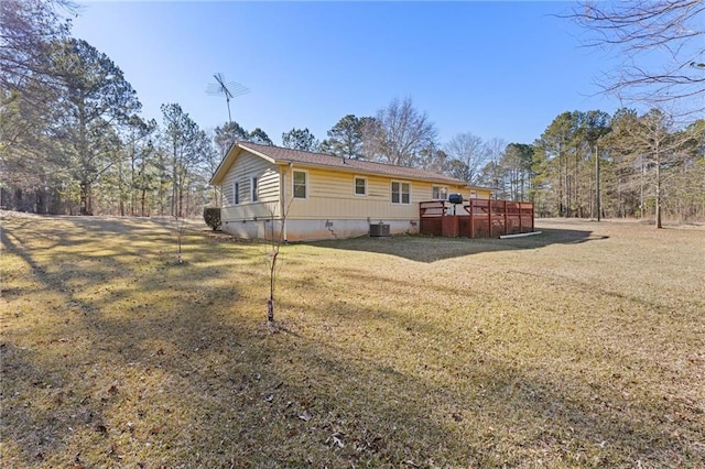 rear view of property featuring a yard, a wooden deck, and central AC