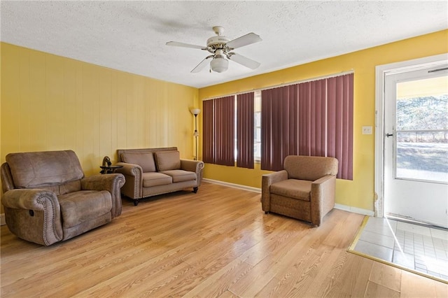 living room featuring ceiling fan, light hardwood / wood-style floors, and a textured ceiling