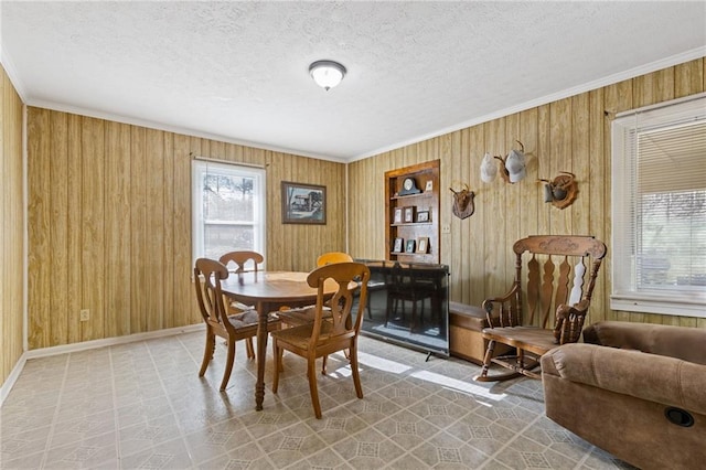 dining room featuring a textured ceiling, crown molding, and wooden walls