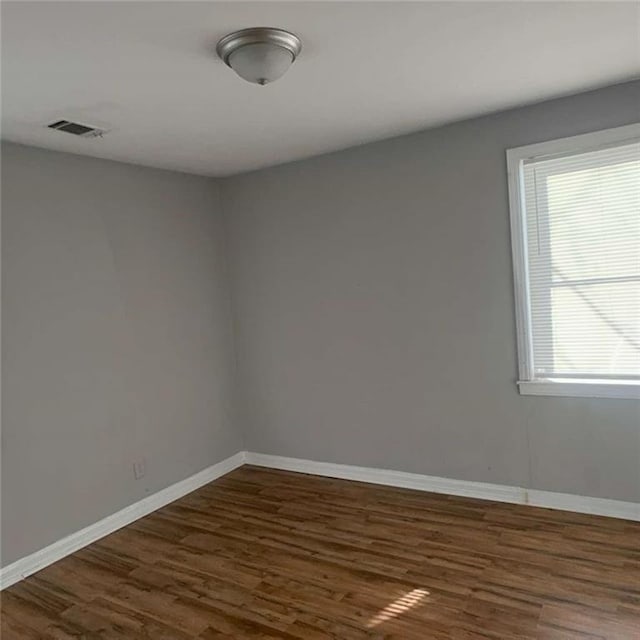 spare room with baseboards, visible vents, and dark wood-type flooring