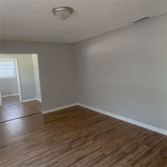 unfurnished room with visible vents, baseboards, and wood finished floors