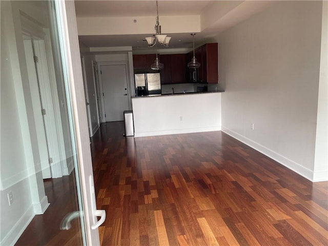 unfurnished living room featuring dark hardwood / wood-style floors and a notable chandelier