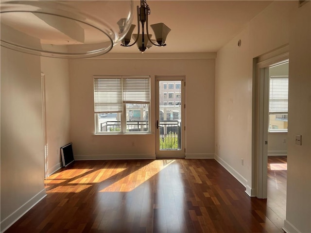 empty room featuring a chandelier and dark hardwood / wood-style flooring