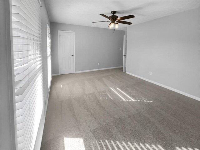 carpeted empty room with a healthy amount of sunlight, baseboards, and ceiling fan