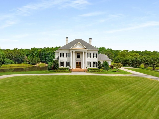 neoclassical home featuring a front lawn and a water view