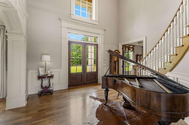 foyer entrance featuring french doors, a towering ceiling, and hardwood / wood-style floors