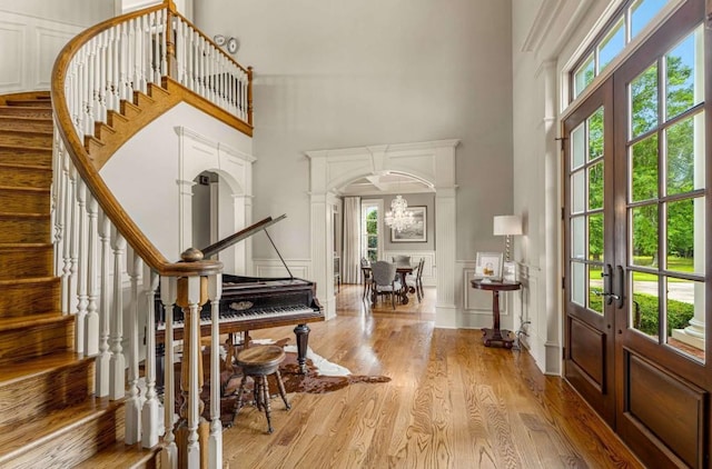 entrance foyer featuring a towering ceiling, french doors, light wood-type flooring, and a wealth of natural light