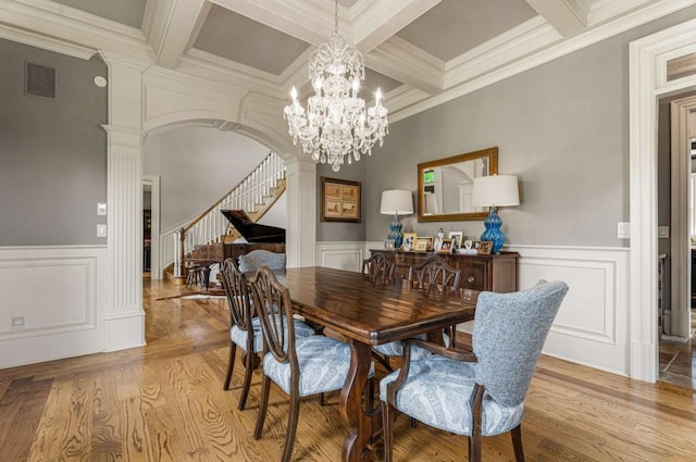 dining area with light wood-type flooring, decorative columns, ornamental molding, coffered ceiling, and beamed ceiling