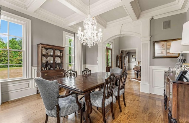 dining space with decorative columns, a wealth of natural light, crown molding, and light hardwood / wood-style floors