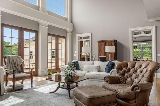 living room featuring decorative columns, a wealth of natural light, french doors, and a towering ceiling