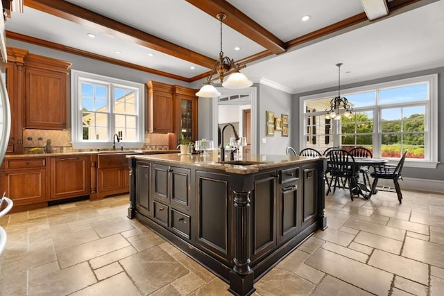 kitchen featuring a kitchen island with sink, an inviting chandelier, sink, hanging light fixtures, and beamed ceiling