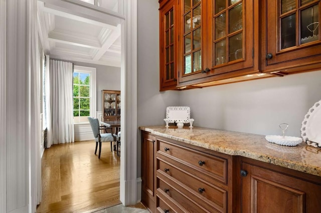 bar featuring beam ceiling, light stone countertops, light hardwood / wood-style flooring, and coffered ceiling