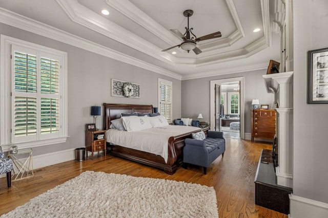 bedroom featuring ceiling fan, wood-type flooring, crown molding, and a tray ceiling