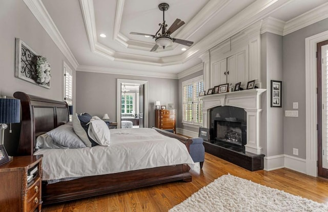 bedroom with ceiling fan, light wood-type flooring, ornamental molding, and a tray ceiling