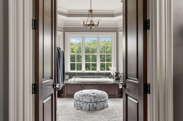 bathroom with a tray ceiling, a tub, crown molding, and an inviting chandelier