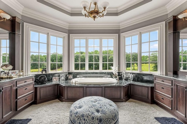 bathroom with a tray ceiling, a bathtub, ornamental molding, and a notable chandelier