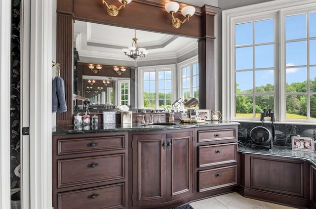 interior space with decorative light fixtures, a healthy amount of sunlight, sink, and dark stone counters