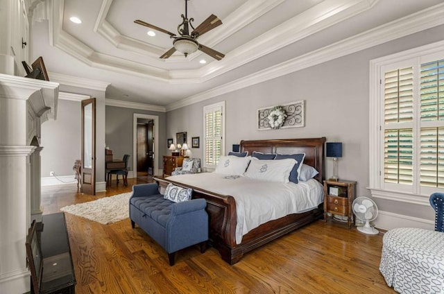 bedroom with hardwood / wood-style floors, a raised ceiling, ceiling fan, and crown molding