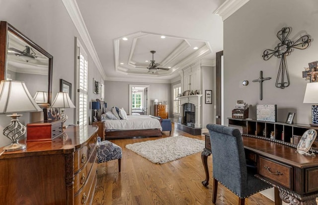 bedroom with hardwood / wood-style floors, a tray ceiling, ceiling fan, and ornamental molding