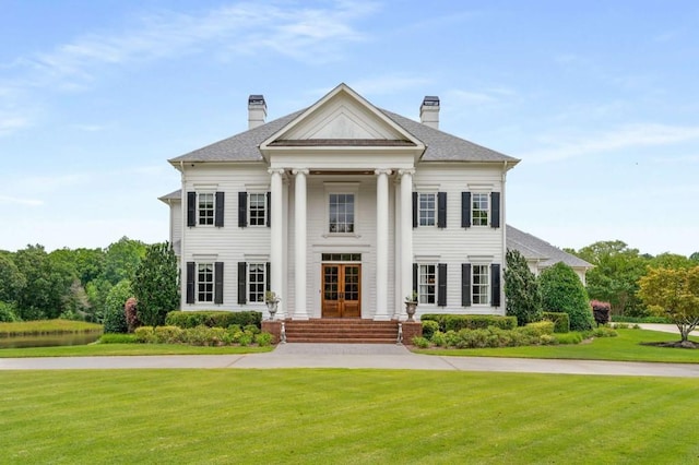 neoclassical home with a front yard and french doors