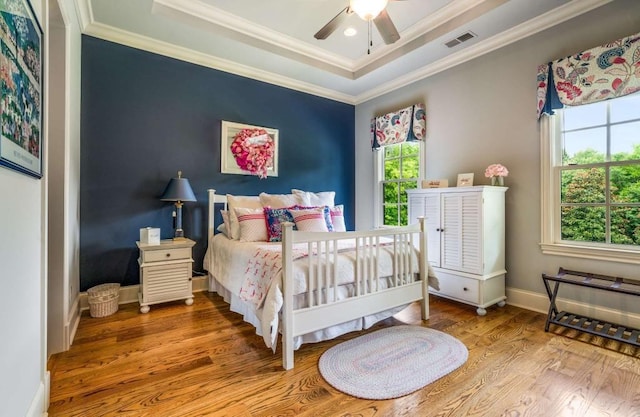 bedroom with a tray ceiling, ceiling fan, crown molding, and wood-type flooring