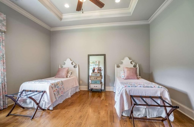 bedroom with ceiling fan, light hardwood / wood-style floors, ornamental molding, and a tray ceiling