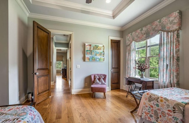 bedroom featuring a raised ceiling, crown molding, and light hardwood / wood-style flooring