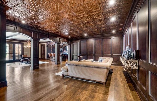 interior space featuring wood walls, ornate columns, dark wood-type flooring, and a chandelier