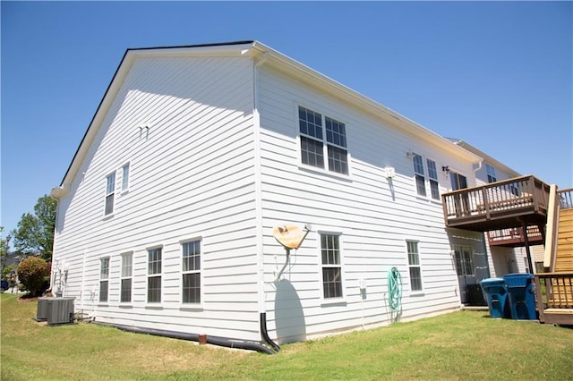 rear view of property featuring a yard, cooling unit, and a deck