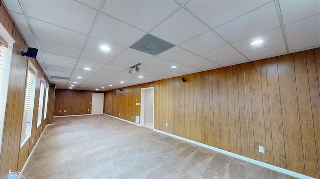 unfurnished room with a paneled ceiling, carpet floors, and wooden walls