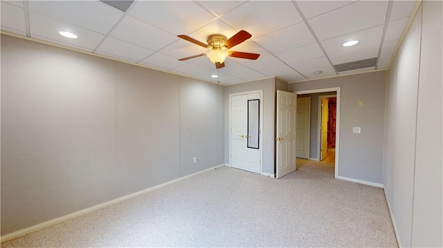 carpeted empty room featuring ceiling fan and a drop ceiling