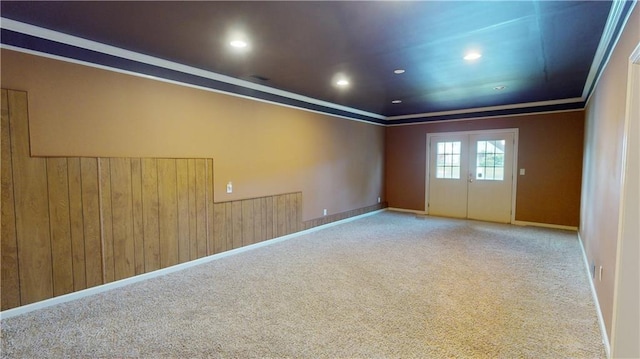 empty room featuring carpet floors, crown molding, and wooden walls