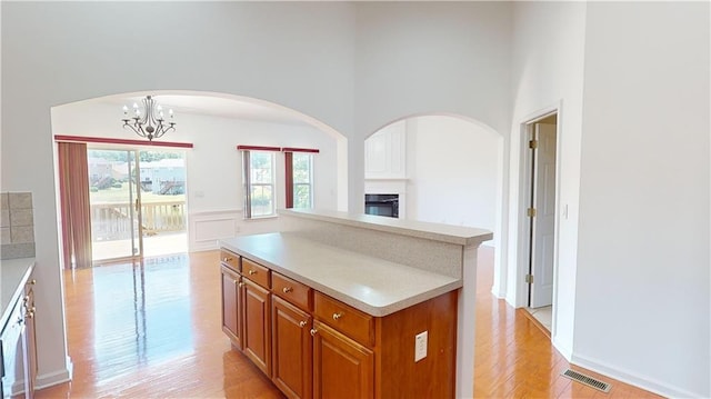 kitchen featuring decorative light fixtures, light hardwood / wood-style flooring, a chandelier, a high ceiling, and a center island