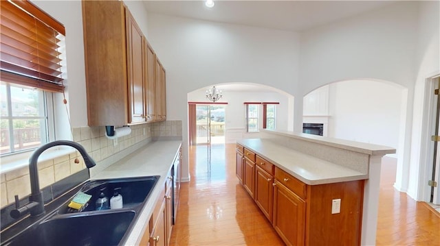 kitchen with a center island, sink, light hardwood / wood-style flooring, tasteful backsplash, and a chandelier