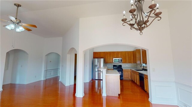 kitchen featuring sink, high vaulted ceiling, wood-type flooring, a kitchen island, and black appliances