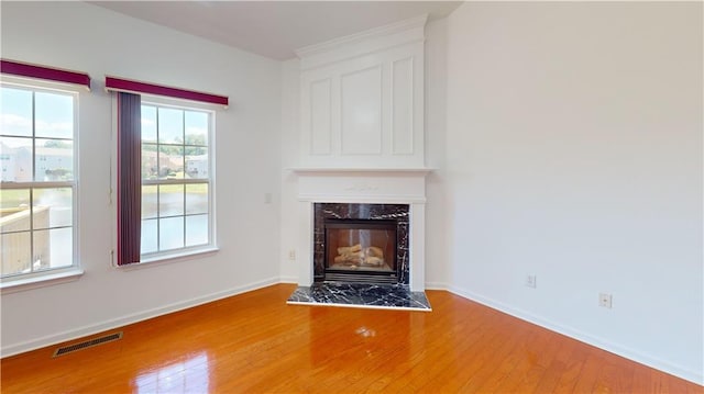 unfurnished living room with hardwood / wood-style floors and a high end fireplace