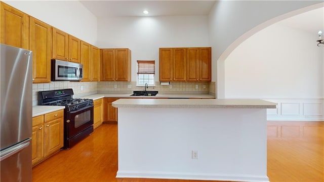 kitchen with appliances with stainless steel finishes, light hardwood / wood-style floors, a kitchen island, and sink