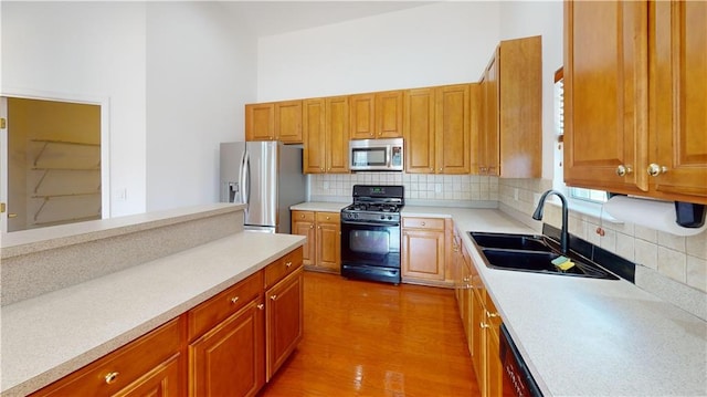 kitchen with tasteful backsplash, stainless steel appliances, hardwood / wood-style flooring, and sink