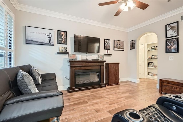 living room featuring crown molding, baseboards, ceiling fan, and light wood-style flooring