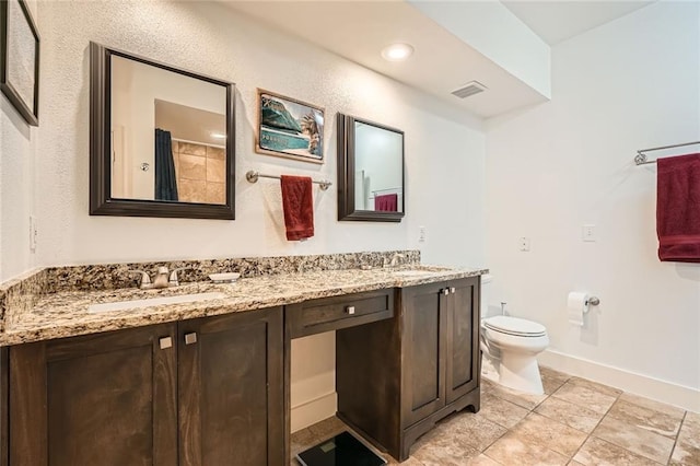 bathroom featuring visible vents, double vanity, toilet, baseboards, and a sink