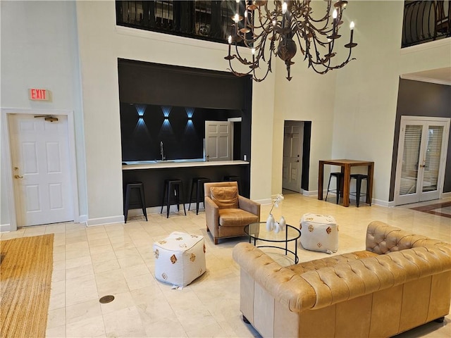 tiled living area featuring an inviting chandelier, baseboards, and a high ceiling