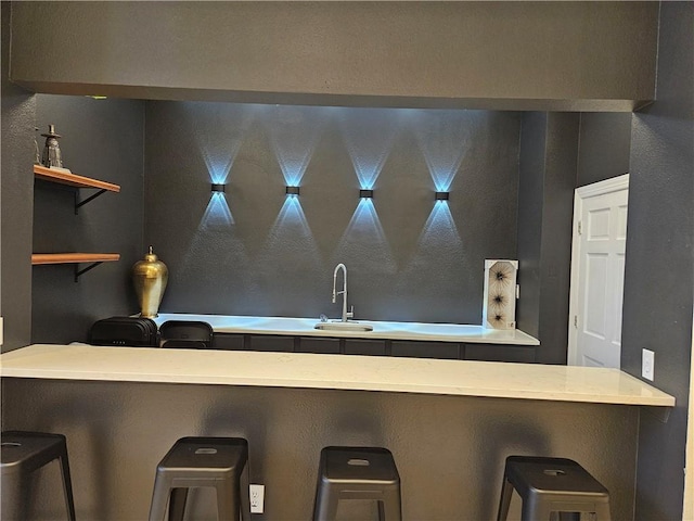 interior space featuring a peninsula, a sink, and a kitchen bar