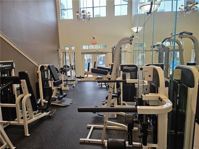 gym featuring a high ceiling, an inviting chandelier, and french doors